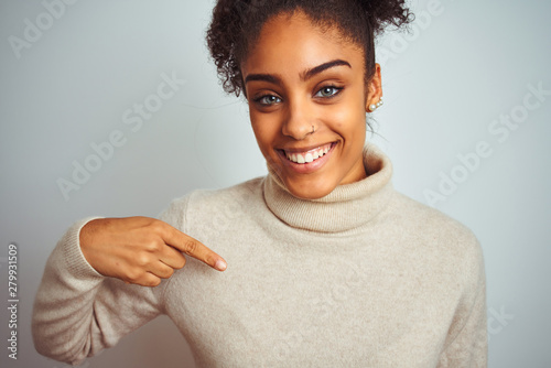 African american woman wearing winter turtleneck sweater over isolated white background with surprise face pointing finger to himself photo