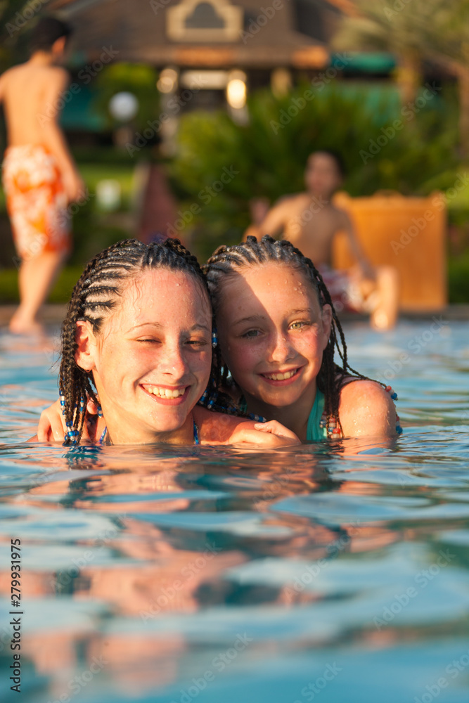 Obraz premium Two girls playing piggy back while swimming in a pool at a resort in Cruz Bay, St. John, USVI