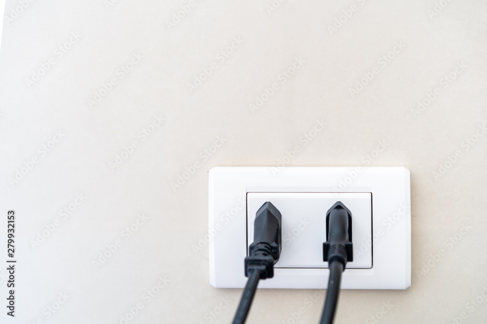 Standard in-wall electric plug sockets pluged in by power cord close up. Standard in-wall electric plug sockets pluged in by power cord close up.