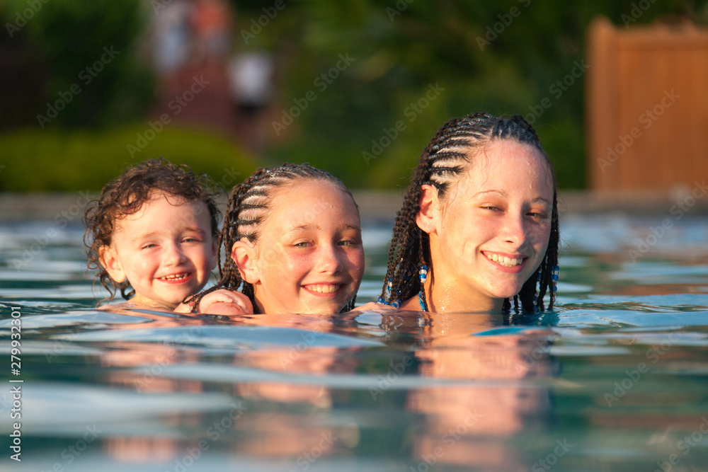 Three children playing piggyback while swimming in a pool in Cruz Bay, St. John, USVI Three children playing piggyback while swimming in a pool in Cruz Bay, St. John, USVI