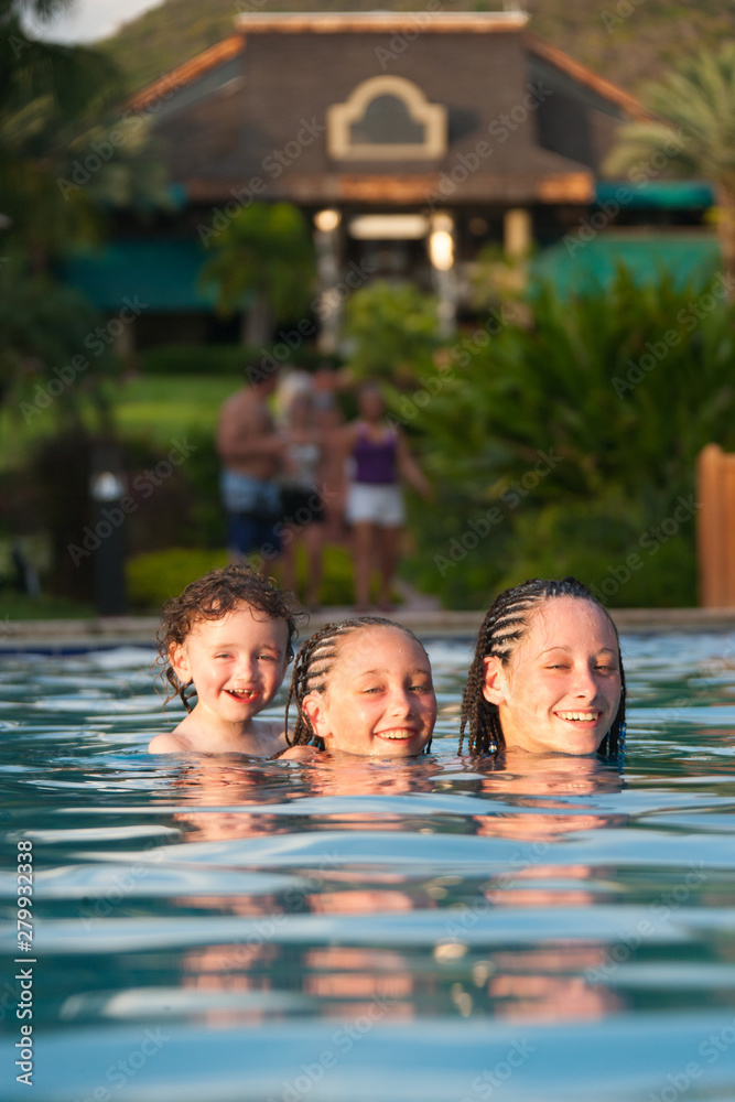 Three children playing piggyback while swimming in a pool in Cruz Bay, St. John, USVI