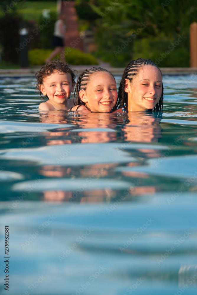 Three children playing piggyback while swimming in a pool in Cruz Bay, St. John, USVI