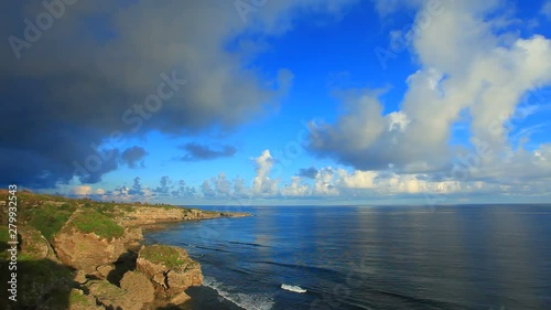 Clouds over rocky sea coast with lighthouse in background photo