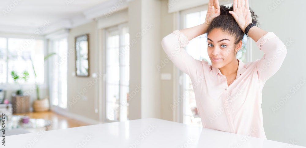 Wide angle of beautiful african american woman with afro hair Doing bunny ears gesture with hands palms looking cynical and skeptical. Easter rabbit concept. Wide angle of beautiful african american woman with afro hair Doing bunny ears gesture with hands palms looking cynical and skeptical. Easter rabbit concept.