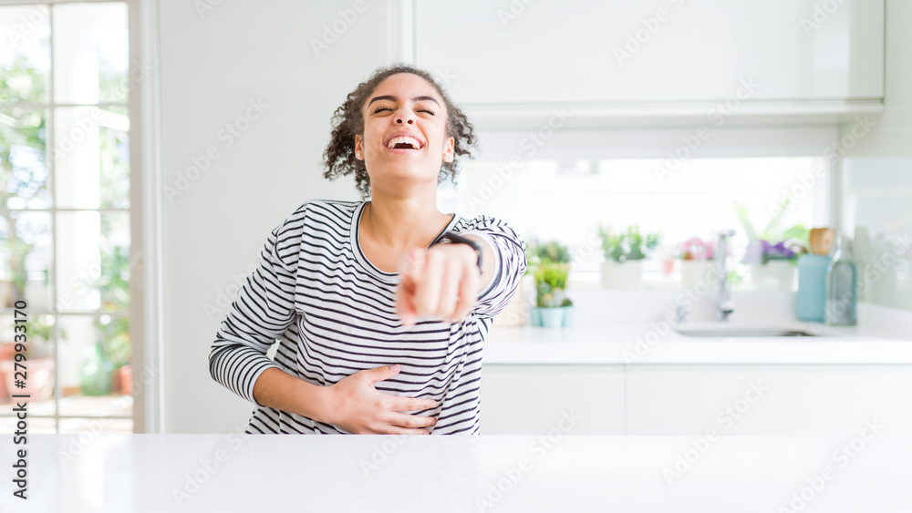 Beautiful african american woman with afro hair wearing casual striped sweater laughing at you, pointing finger to the camera with hand over body, shame expression Beautiful african american woman with afro hair wearing casual striped sweater laughing at you, pointing finger to the camera with hand over body, shame expression