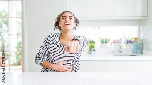 Beautiful african american woman with afro hair wearing casual striped sweater laughing at you  pointing finger to the camera with hand over body  shame expression