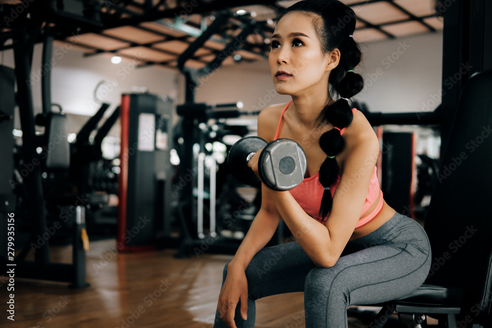 Fototapeta premium sport woman at fitness gym club doing exercise for arms with dumbbells and showing muscle bodybuilding, fitness concept, sport concept