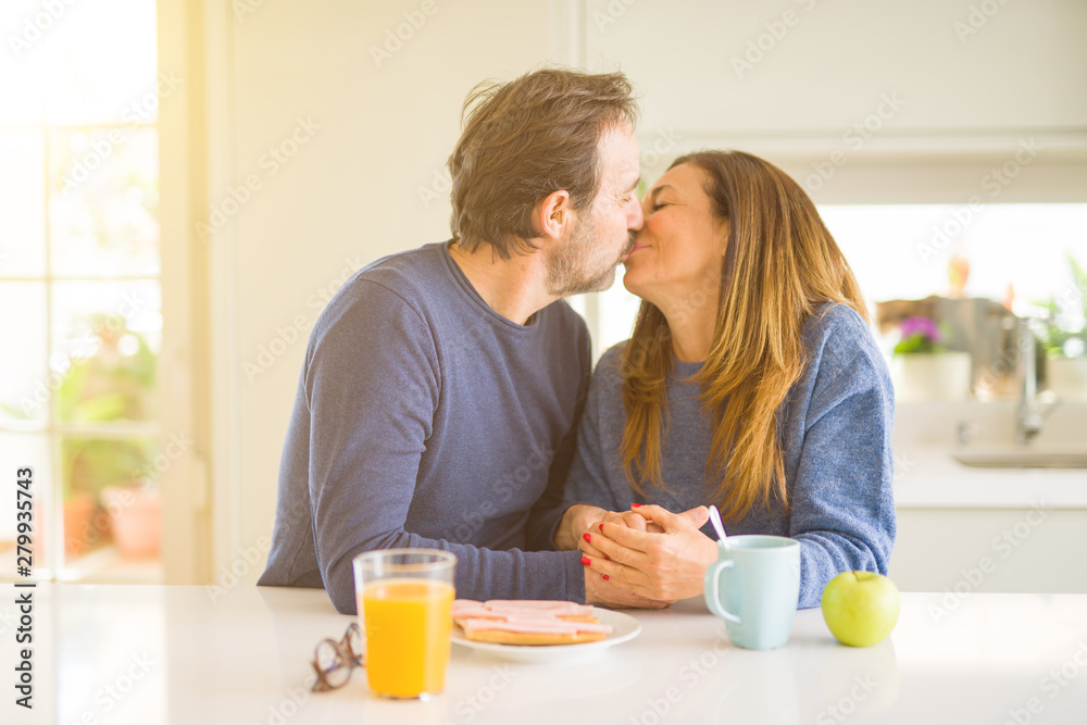 Beautiful romantic middle age couple kissing having healthy breaskfast in the morning at home