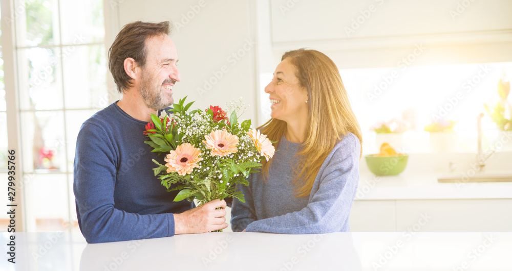 Romantic middle age couple holding flowers in love at home Romantic middle age couple holding flowers in love at home