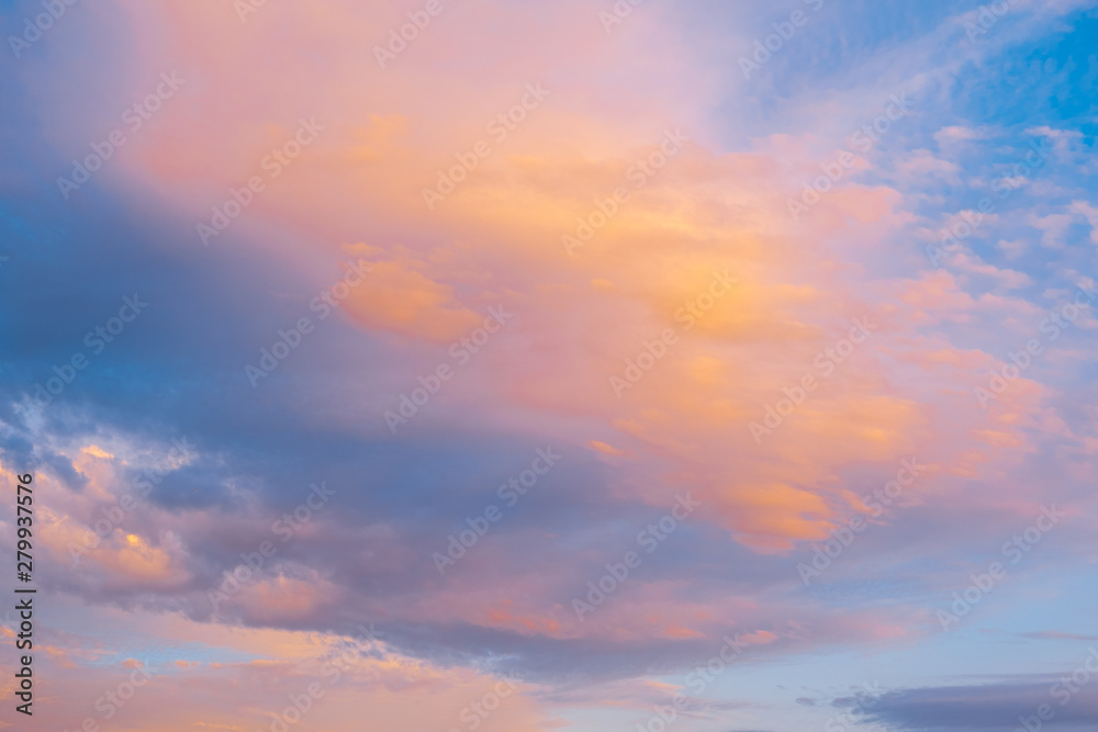 Blue sky with clouds glowing in orange hues at sunset