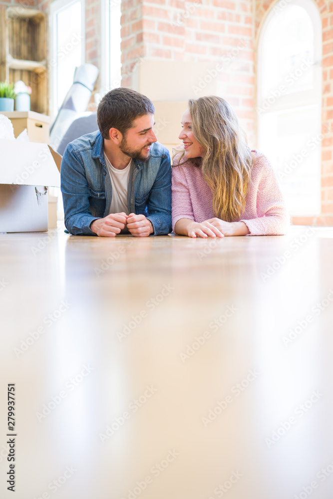 Young beautiful couple in love relaxing lying on the floor together with cardboard boxes around for moving to a new house Young beautiful couple in love relaxing lying on the floor together with cardboard boxes around for moving to a new house