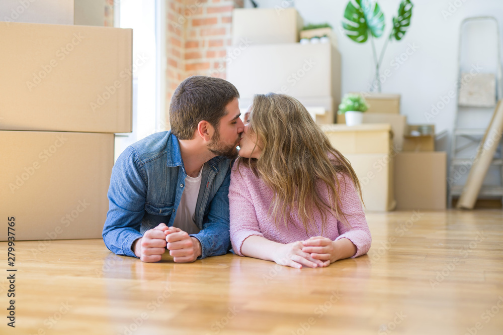Young beautiful couple in love relaxing lying on the floor together with cardboard boxes around for moving to a new house Young beautiful couple in love relaxing lying on the floor together with cardboard boxes around for moving to a new house