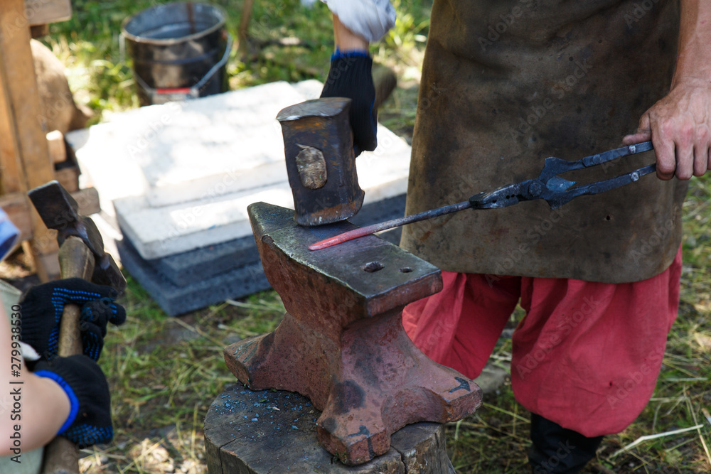 Forge. The blacksmith processes the heated metal with a sledgehammer on the anvil. Manual work of a blacksmith.