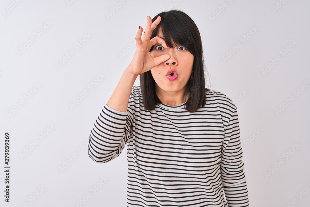Young beautiful chinese woman wearing black striped t-shirt over isolated white background doing ok gesture shocked with surprised face, eye looking through fingers. Unbelieving expression. Young beautiful chinese woman wearing black striped t-shirt over isolated white background doing ok gesture shocked with surprised face, eye looking through fingers. Unbelieving expression.