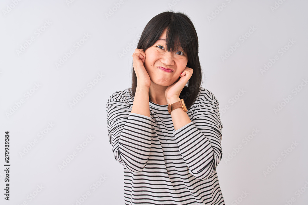 Young beautiful chinese woman wearing black striped t-shirt over isolated white background covering ears with fingers with annoyed expression for the noise of loud music. Deaf concept. Young beautiful chinese woman wearing black striped t-shirt over isolated white background covering ears with fingers with annoyed expression for the noise of loud music. Deaf concept.