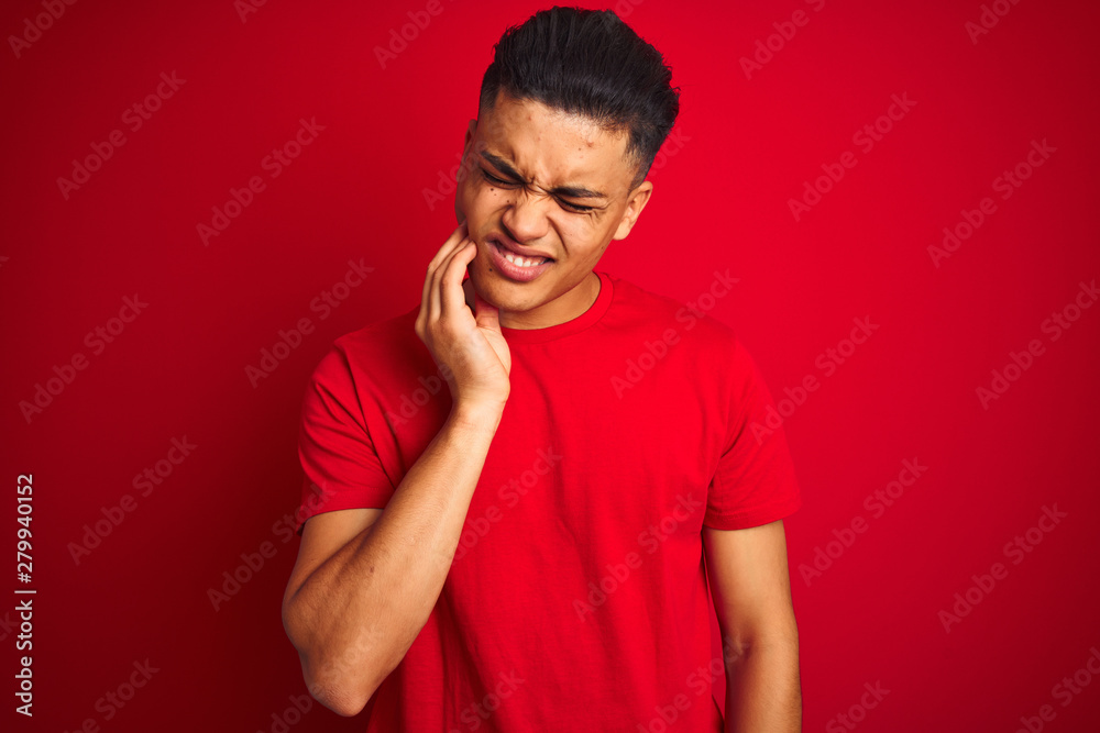 Young brazilian man wearing t-shirt standing over isolated red background touching mouth with hand with painful expression because of toothache or dental illness on teeth. Dentist concept. Young brazilian man wearing t-shirt standing over isolated red background touching mouth with hand with painful expression because of toothache or dental illness on teeth. Dentist concept.