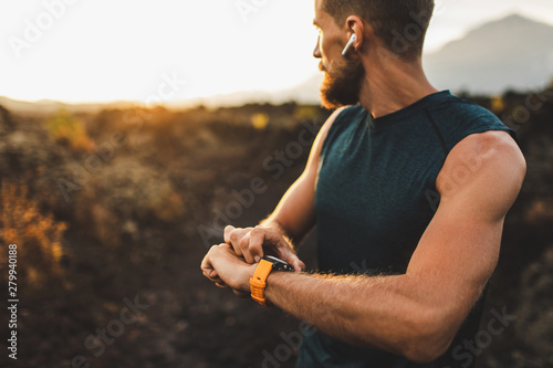 Athletic runner start training on fitness tracker or smart watch and looking forward on horizon. Trail running and active lifestyle concept.