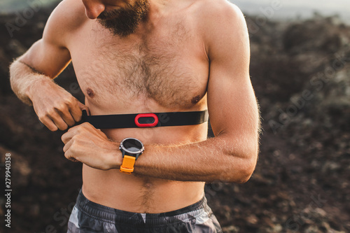 Obraz na plátně Male runner wearing professional chest heart rate monitor and preparing for trail running outdoors