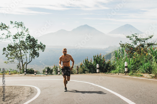 Fotografía Man running topless in uphill on the asphalt road in hot summer weather