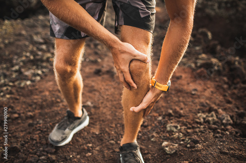 Knee injury on running outdoors. Man holding knee by hands close-up and suffering with pain. Sprain ligament or meniscus problem. photo