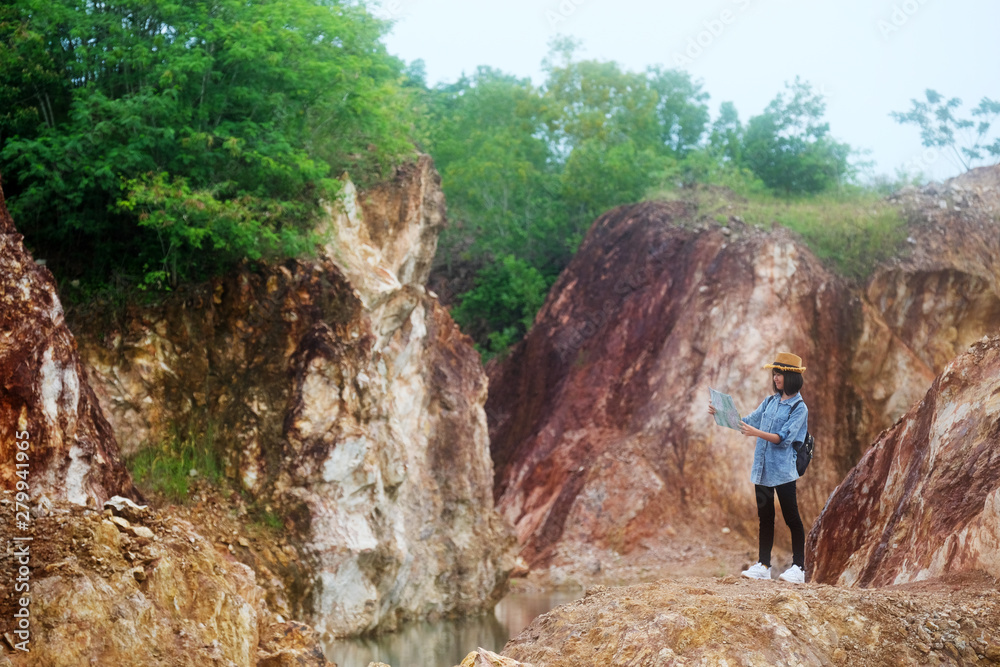 Solo travel in local asia, Teenager traveler holding map while hiking on mountain, Solo tourist traveller with map standing on top of stone hill background, Summer happy travel vacation in local asia