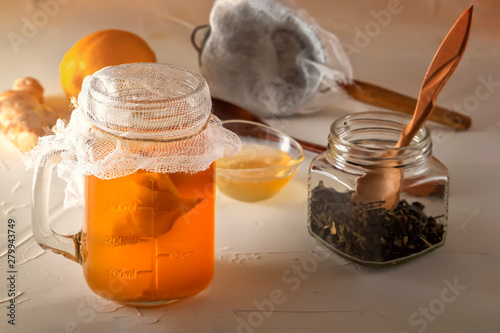 Homemade fermented drink Kombucha in glass jar with lemon and honey on a wooden table. Close-up