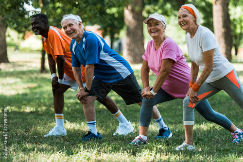 happy senior and multicultural people exercising on grass