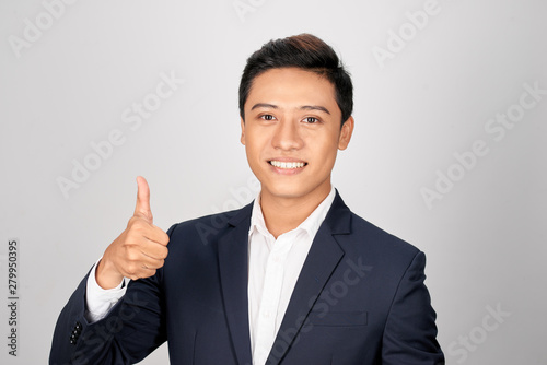 Asian smiling businessman showing thumb up one hand, isolated on white background