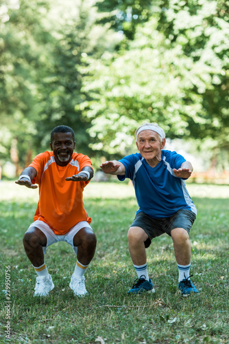 cheerful retired and multicultural med doing sit ups on grass © LIGHTFIELD STUDIOS