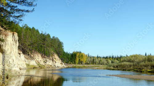 Pine forest on the clay rock near the shore of the river Kempendyay in the wild tundra of Northern Yakutia in the sunset of the evening, bright in the autumn. photo