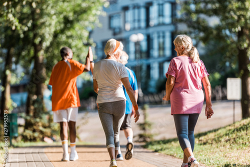 selective focus of senior women running near multicultural retired men