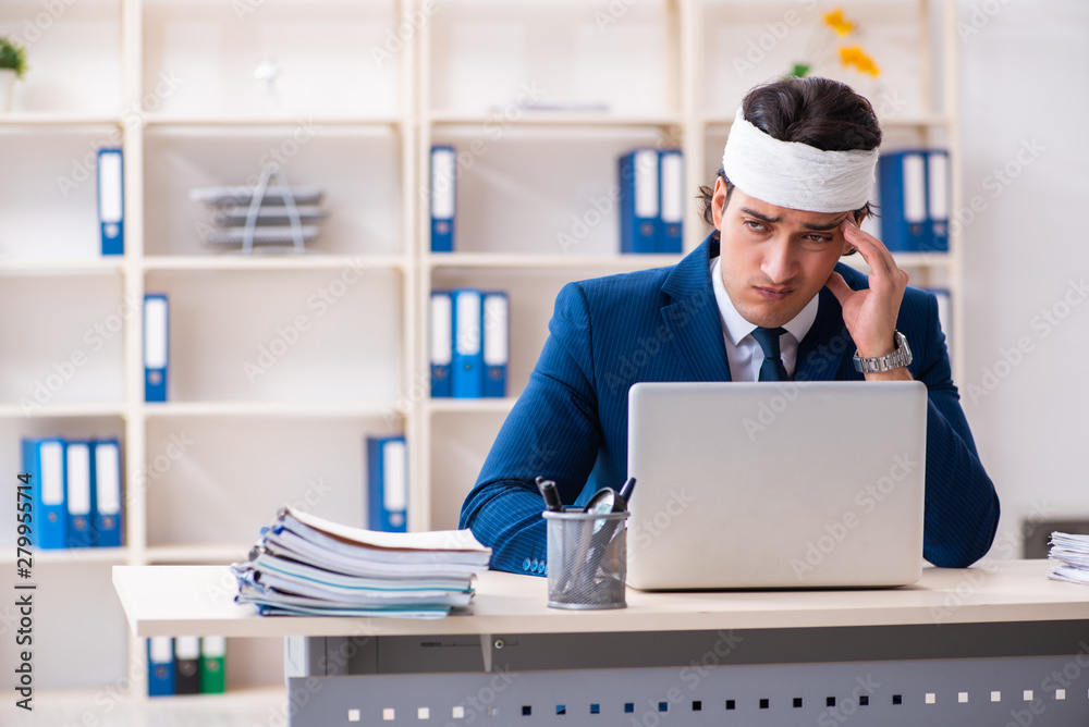Head injured male employee working in the office Head injured male employee working in the office