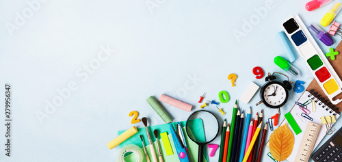 Set of different stationery, alarm clock and colorful supplies on blue background. Back to school concept. Banner format. Top view.