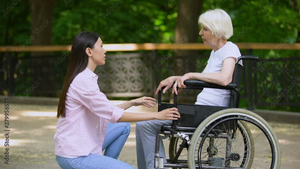 Volunteer talking with crying woman in wheelchair, psychological support, park Volunteer talking with crying woman in wheelchair, psychological support, park
