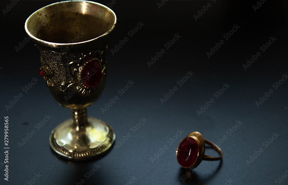 Silver cup and ring with red rubin, antiques on black background