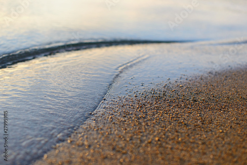 Sea wave and sand seashore. Golden sun light over the sea ocean waves. MIrror reflection on water surface. Macro close up. © evso