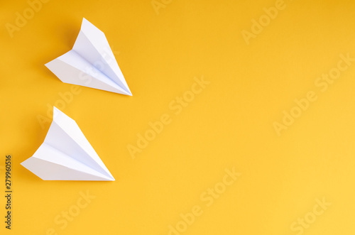 White paper planes on yellow background composition.