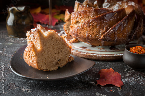 Bundt cake with saffron and rum covered with white glaze on rustic background with autumn decorations photo