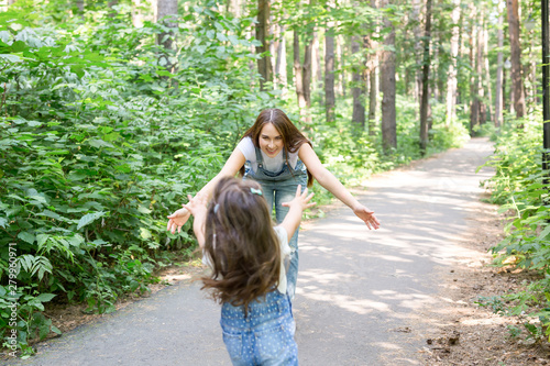 Nature, family, people concept - Adorable little kid girl and young woman in beautiful forest. Daughter running to mother photo