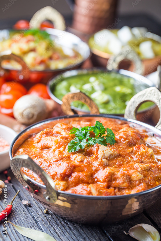 Different bowls with assorted indian food on dark wooden background. Chicken, curry rice, lentils, paneer, chapati and spices. Different bowls with assorted indian food on dark wooden background. Chicken, curry rice, lentils, paneer, chapati and spices.