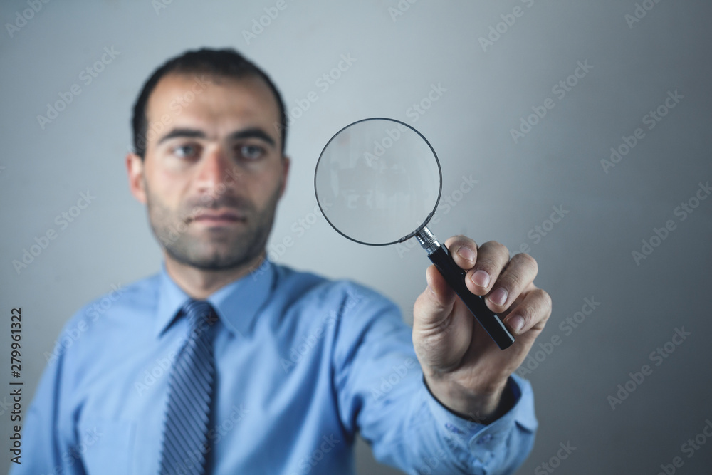 Caucasian businessman holding magnifying glass.