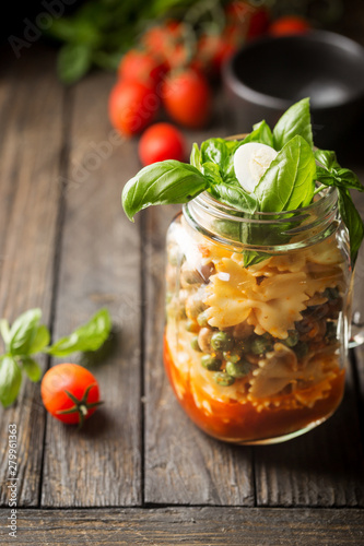 Italian Pasta with tomato sauce, mushrooms, peas and cheese in a jar. Food for work and office