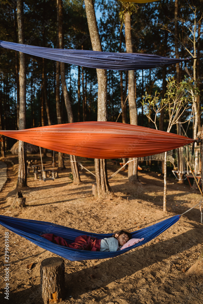 young asian kid relaxing on hammock outdoor in the wood