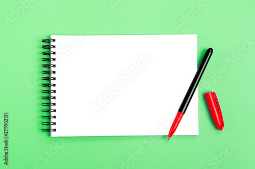 school notebook and red pen on green light background, spiral notepad on a table Top view Flat lay