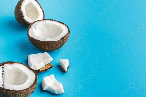 Slices of broken tropical coconuts on blue background. Top view