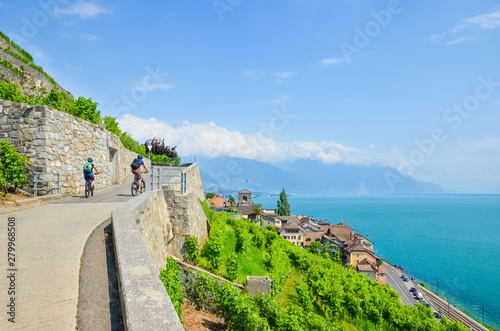 Cyclist on scenic path along green terraced vineyards on the slopes adjacent to Geneva Lake, Switzerland. Lavaux wine region. Switzerland in summer. Swiss landscape. Cycling. Sport tourism
