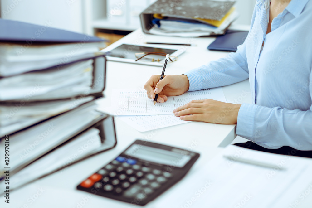Naklejka premium Unknown female bookkeeper or financial inspector calculating or checking balance, making report, close-up. Internal Revenue Service at work with financial document. Tax and audit concept