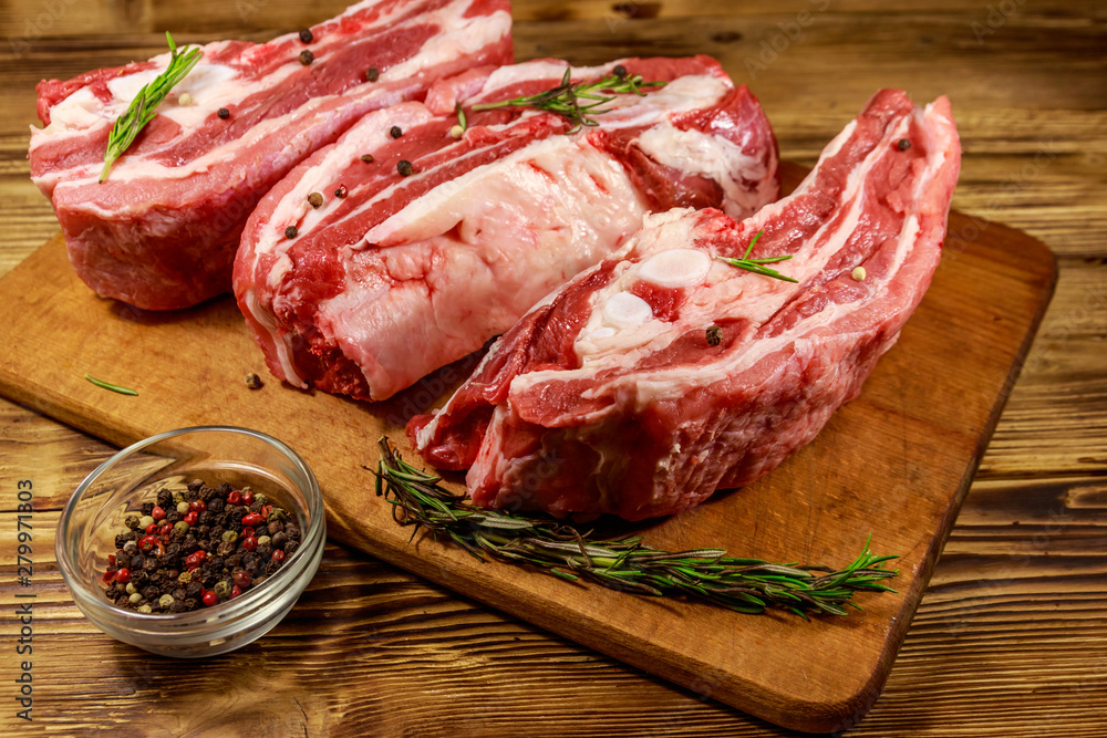 Raw pork ribs with spices and rosemary on wooden table