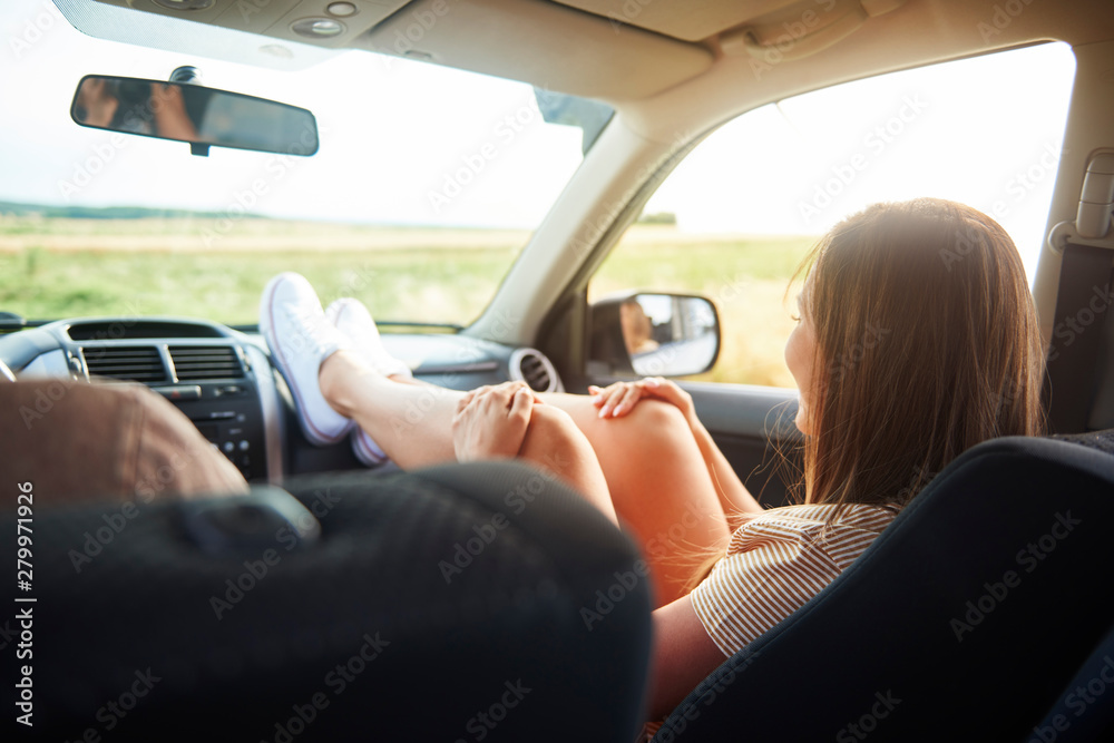 Woman holding her legs on dashboard in car