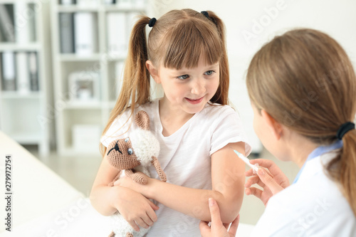 Doctor vaccinating little g...